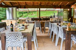 An outdoor covered shared entertaining space with a professional kitchen, where the owners host invited guests for informal social gatherings