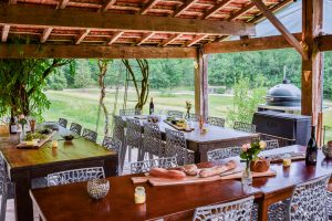 An outdoor covered shared entertaining space with a professional kitchen, where the owners host invited guests for informal social gatherings