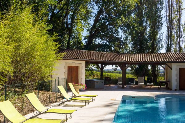 Shadied seating by the pool, loungers and a table, vineyard views